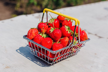 Mini shopping basket full of fresh red ripe strawberry on vintage background