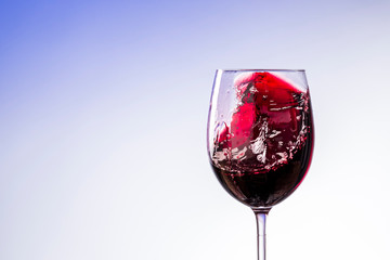 splash of wine in a glass close up on a blue and white background