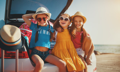 happy children girls friends sisters on the car ride to summer trip.