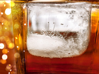 Big Ice Cube in a Glass of Whiskey and Coke Drink. Ice Texture Details. Celebration Lights.