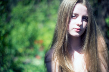 Naklejka premium beautiful young blonde with her long hair against a background of greenery