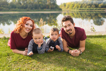 Fototapeta premium Children, parenthood and nature concept - Big family lying on the grass