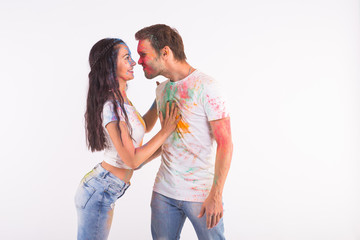 Friendship, love, festival of holi, people concept - young couple playing with colors at the festival of holi on white background with copy space