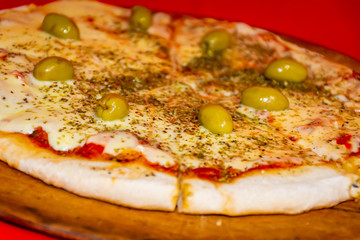  Pizza with mozzarella cheese and green olives, red background.