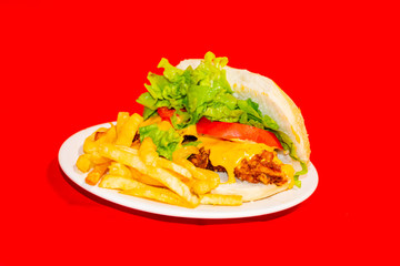 Sandwiches fried chicken, tomatoes, lettuce leaves and French fries with red background.