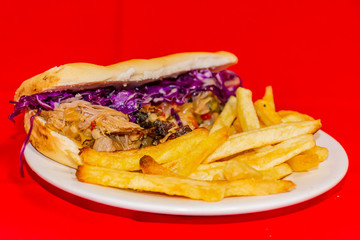 Pork cabbage sandwiches and fries. Plated with a red background.