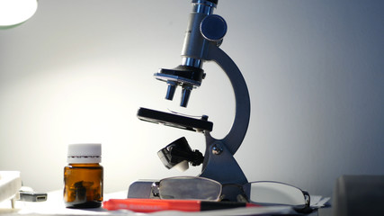 Researching Activity in a Lab with Microscope End Medical Pills on the Table