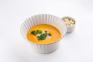 Pumpkin soup with cream and pumpkin seeds and croutons isolated on white background