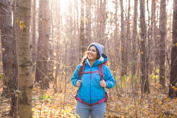 adventure, travel, tourism, hike and people concept - smiling tourist woman walking with backpacks over autumn natural background