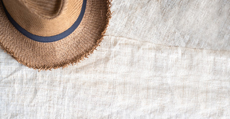 Fototapeta na wymiar Top view of Summer brown panama straw hat on linen cloth.travel concept.copy space for adding text