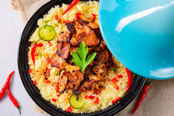 Tajin with couscous, vegetables and meat on white background