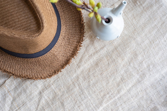 Top view of Summer brown panama straw hat with flower plant in vase on linen cloth.travel concept.copy space for adding text