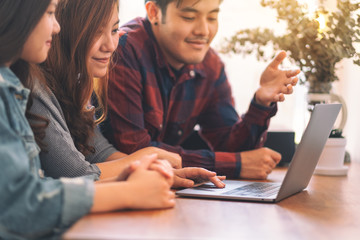 Three young asian people using and looking at the same laptop computer during a meeting