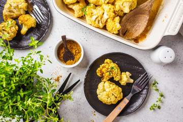 Vegan flat lay of baked cauliflower  white concrete background, top view.