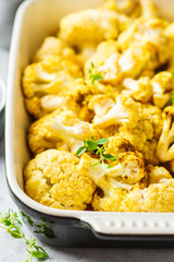 Baked cauliflower in oven dish on white concrete background.