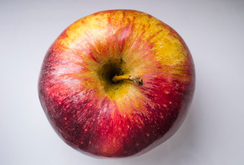 Ripe whole red apple on light background top down view. Soft drop shadow with natural light. Close up.