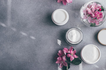 Natural cosmetics skin care. Composition of a jar of cream and bloomed spring flowers. Flat lay.