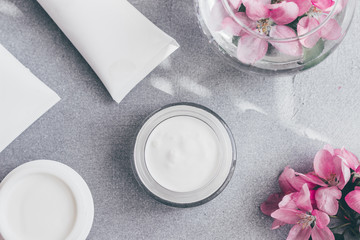 Natural cosmetics skin care. Composition of a jar of cream and bloomed spring flowers. Flat lay.