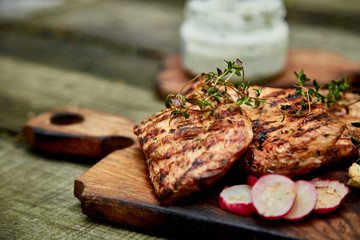 Grilled turkey meat. Steak turkey grill on wooden cutting board with a variety of grilled vegetables on  rustic background  Top view. Flat lay. Copy space..