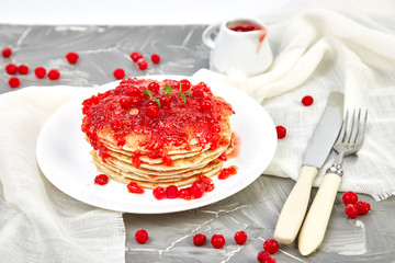 American pancake with jam - berry, viburnum, cranberry on grey background. Homemade pancakes with berry sauce and mint. Healthy breakfast with fresh hot pancakes with berry jam
