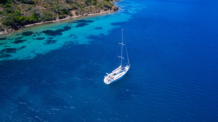 Aerial view of sea and yacht. Sailing ship in the middle of ocean, top view, summer background. Amazing view to Yacht sailing in open sea at sunny day