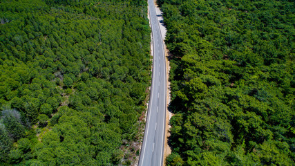 Fototapeta na wymiar Aerial view from above of country road through the green summer forest in summer Turkey. Top view of the asphalt road and dense green forests