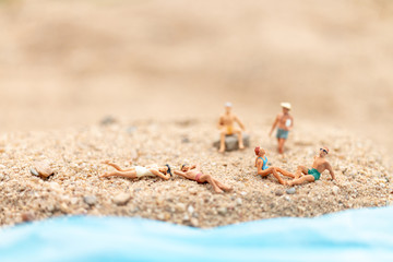 Miniature people wearing swimsuit relaxing on the beach , Travel and Summer concept