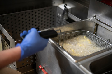 Cocinando patatas fritas en freidora de restaurante de comida rápida