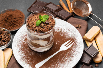 Classic tiramisu dessert in a glass on dark concrete background