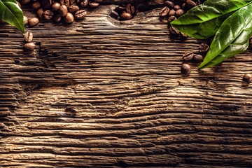 Top of view coffee beans and green leaves on rustic oak table