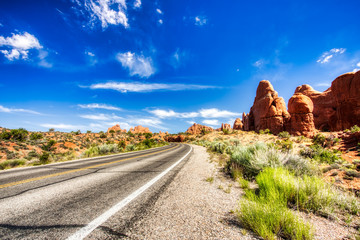 Driving through the-Desert with Monument Rock along the Road During Sunny Day, Arches NP