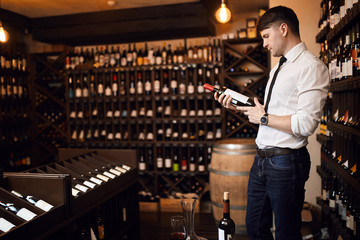 handsome man choosing best international Austrian wine. side view photo. copy space.clever cute man specializes in all aspects of wine service. food concept