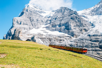 Jungfrau Eigergletscher snowy rocky mountain and red train in Switzerland - obrazy, fototapety, plakaty