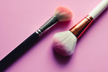 Two used make up brushes on the pink background. Fashion concept.