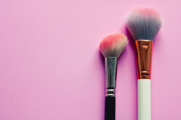 Make up brushes isolated on pink background. Top view cosmetic concept.