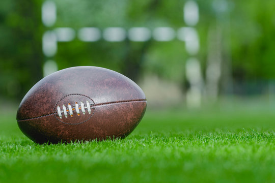 American football, rugby ball on green grass field background