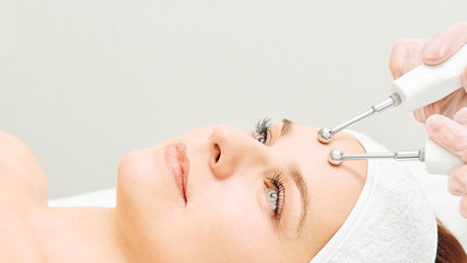 Microcurrent esthetics procedure. Beauty girl face. Cosmetology machine. Doctor hands. Two micro...