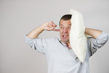 Sleepy man with pillow closing his ear