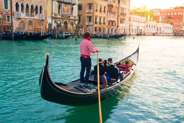 Fototapeta na wymiar Gondolier carries tourists on gondola Grand Canal of Venice, Italy