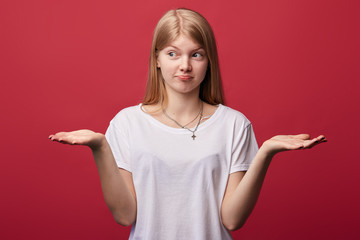 puzzled young funy woman in casula clothes shrugs shoulders and faces dilemma, making choice, girl...