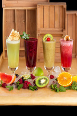 Group of fresh healthy fruit smoothies at wooden table background with ingredients around.