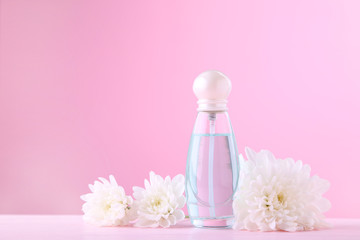 Bottle of perfume with white flowers on pink background