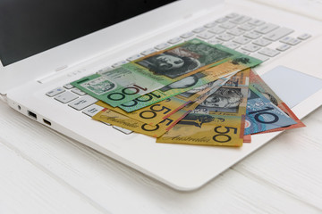 Australian dollar banknotes on white laptop keyboard