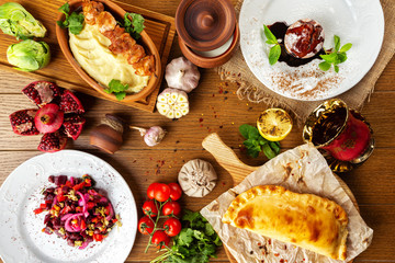Top view image of traditional georgian lunch with various meals and ingredients at decorated wooden table background.