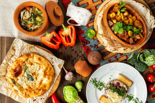 Top view image of traditional georgian lunch with various meals and ingredients at decorated wooden table background.