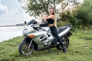 Obraz na płótnie Canvas A beautiful blonde woman sitting on a motorcycle