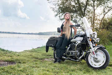 Fototapeta na wymiar Beautiful young woman posing with motorcycle outside