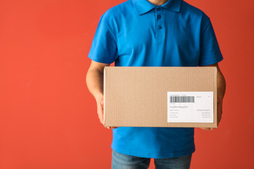 Delivery man with box on color background