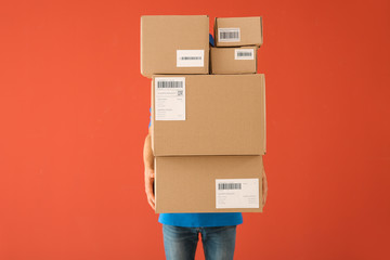 Delivery man with boxes on color background