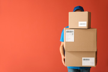 Delivery man with boxes on color background